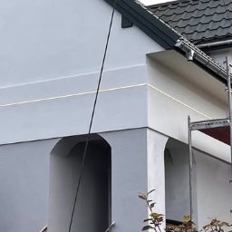 Marwikt Usługi Budowlane - Jasnoszara elewacja domu po tynkowaniu w Tomaszowie Mazowieckim, widoczne rusztowanie i subtelne detale architektoniczne.