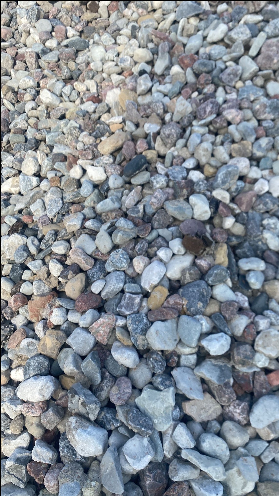 Mieszanka drobnych kamieni o różnej kolorystyce: szare, białe, różowe i brązowe odcienie, tworzące naturalną teksturę.