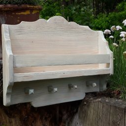 Maciej Borowiec - Drewniana półka w stylu rustykalnym, z haczykami i przegródkami, pomalowana na biało-szary kolor, ustawiona na pniu drzewa w ogrodzie.