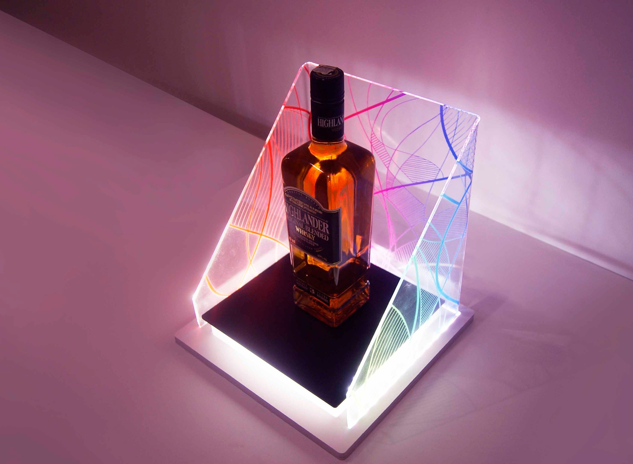 Butelka whisky na podświetlonej, geometrycznej ekspozycji z akrylu, z gradientem kolorów, na białym tle.