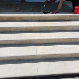 E-M Jerzy MIOSGA - Kamienne schody zewnętrzne czyszczone pędzlem; widoczny czerwony pojemnik z napisem KEMA i fragment kostki brukowej.