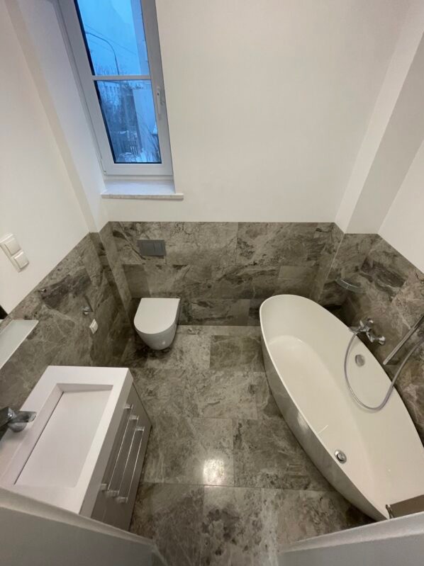 Nowoczesna łazienka z marmurowymi płytkami, owalną wanną wolnostojącą i oknem dachowym, widok z góry.