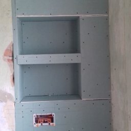 TOMMY-BUD - Ściana z płyty karton gips z wnękami i otworem na instalację elektryczną, widoczne ślady po ołówku, surowy stan wykończenia.