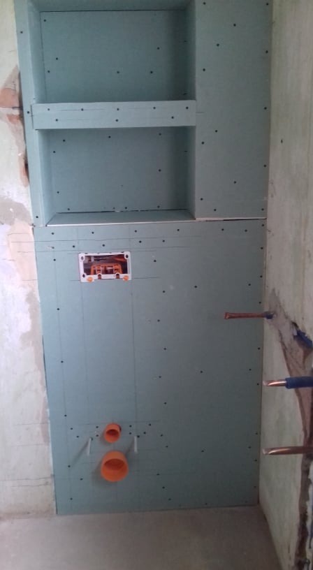 Konstrukcja z płyty karton-gips z wnęką i instalacją hydrauliczną oraz elektryczną w trakcie montażu w łazience.