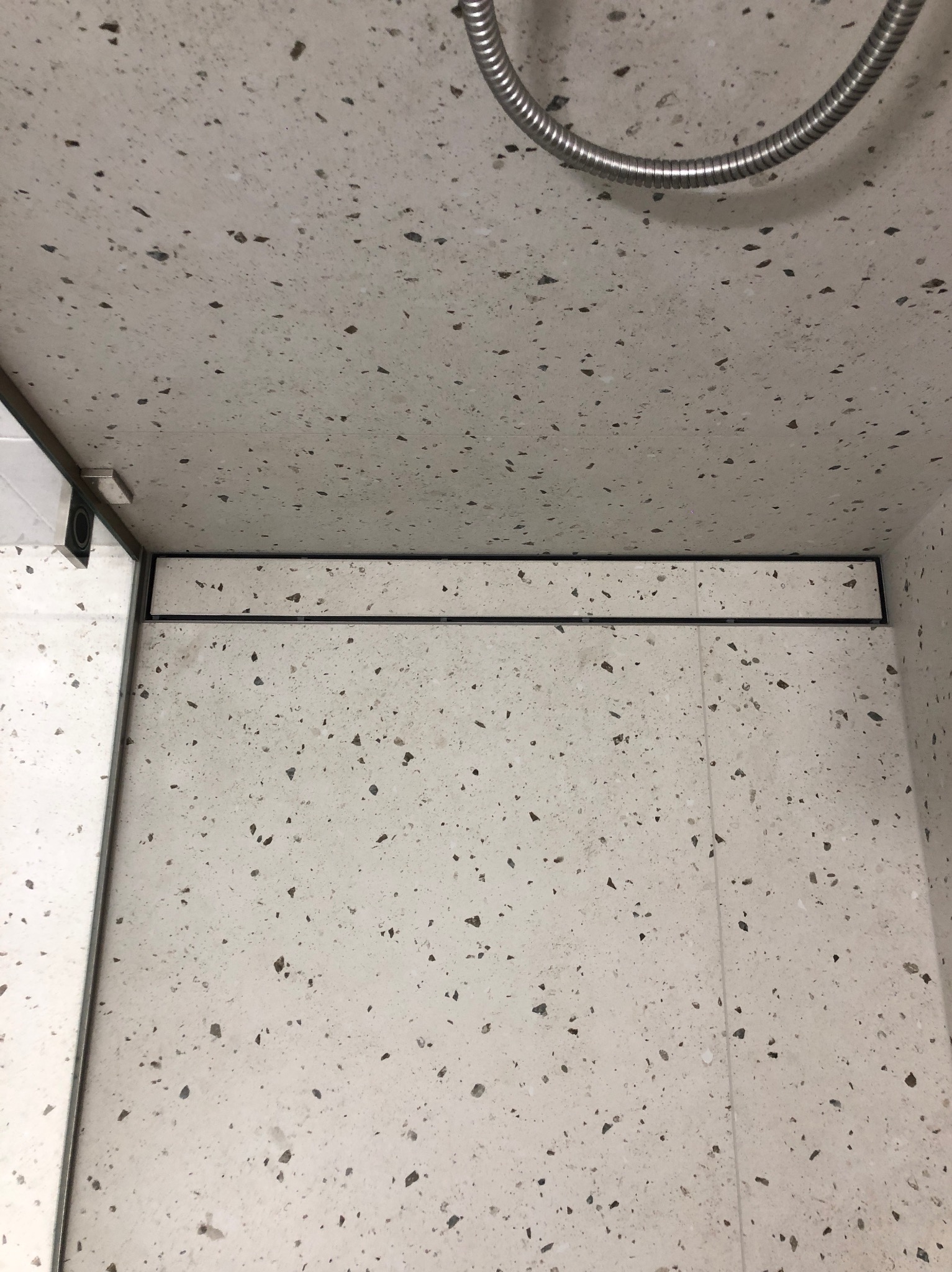 Wykończona kabina prysznicowa z odpływem liniowym i panelami ściennymi imitującymi lastryko.