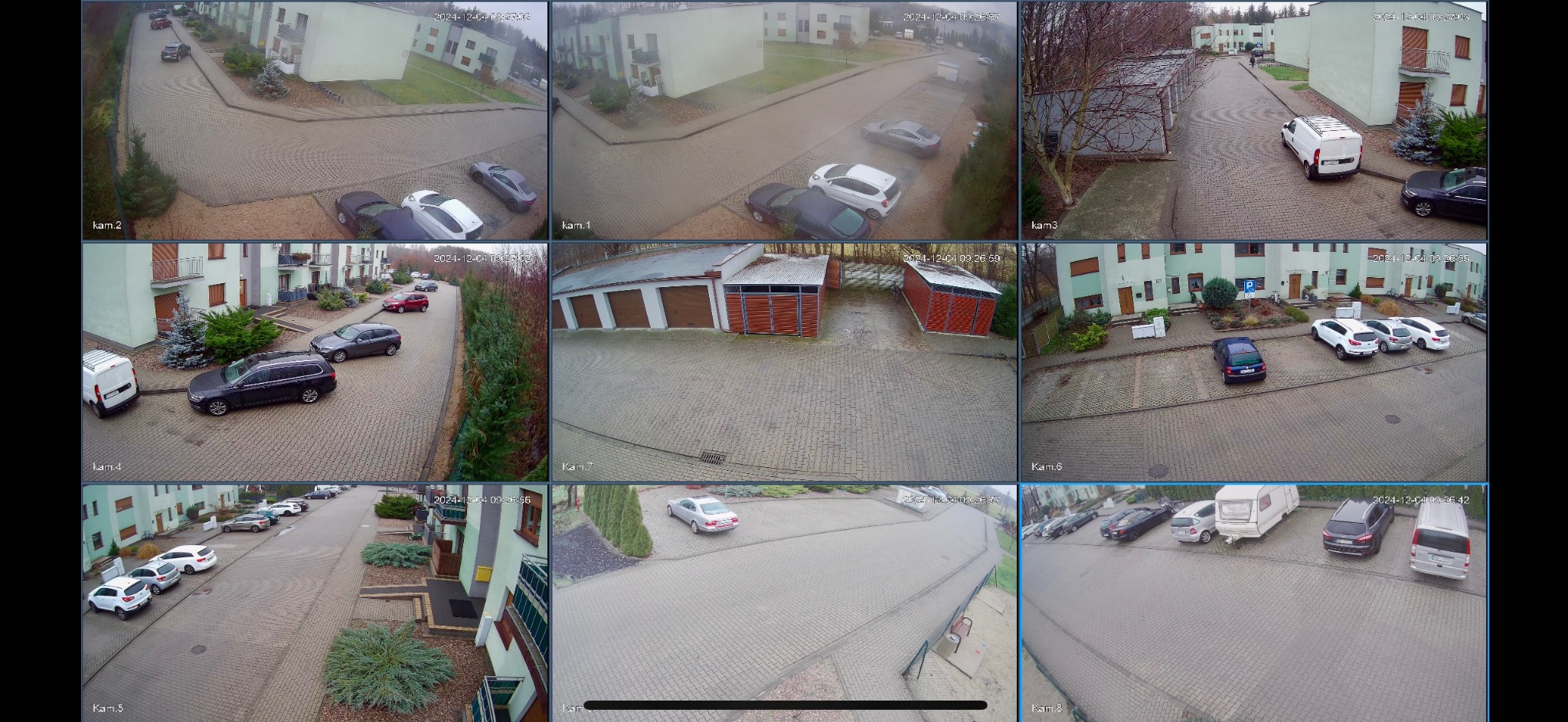 Zestaw ujęć z kamer monitoringu osiedla mieszkaniowego w Środzie Wielkopolskiej, prezentujący widok na parkingi, drogi dojazdowe i budynki z różnych perspektyw.