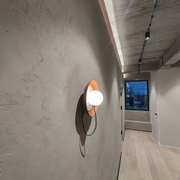 PROFITECH - Borys Tustanovskyi - Minimalistyczne wnętrze korytarza z betonowym sufitem i oświetleniem punktowym, ściana z dekoracyjną fakturą i okrągłym, pomarańczowo-białym kinkietem.