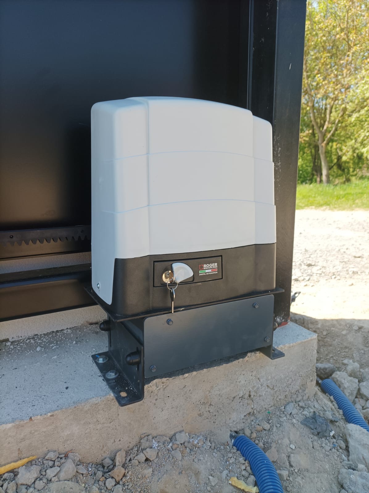 Automat do bramy przesuwnej, zamontowany na podstawie do fundamentu. Napęd bezszczotkowy Roger Technology.