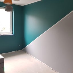 Solid-Art - Pomieszczenie po malowaniu ścian: jedna ściana pomalowana w połowie na szaro, a druga na ciemny turkus, widoczne dwa nowoczesne abażury, ściany pomalowane z precyzją.