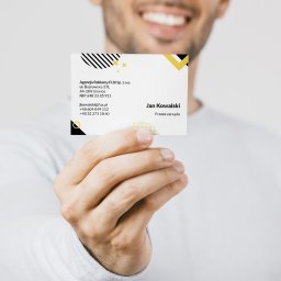 AGENCJA REKLAMY FUX SP.Z O.O. - Mężczyzna trzymający wizytówkę Agencji Reklamy FUX Sp. z o.o. z Gliwic, z danymi kontaktowymi Jana Kowalskiego, Prezesa Zarządu, na białym tle.