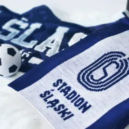 Szale kibica w barwach biało-niebieskich z napisem 'Stadion Śląski' i symbolem stadionu, obok mała piłka nożna.