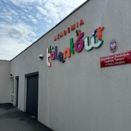 “ J&P.B ” Mycie dachów i elewacji - Elewacja budynku z kolorowym napisem 'Akademia Talentów' i tabliczką informacyjną 'Niepubliczne Przedszkole Akademia Talentów w Osnie Lubuskim', widoczny fragment rynny i chodnik z kostki brukowej.