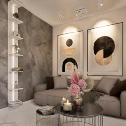 Nowoczesny salon z szarą sofą, okrągłym stolikiem kawowym z kwiatami i świecami, abstrakcyjnymi obrazami na ścianie oraz podświetlaną p&oacute;łką z dekoracjami i książkami, oświetlony projektorem.