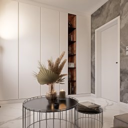 WhiteHouse - Nowoczesne wnętrze salonu z marmurową podłogą, minimalistyczną zabudową meblową, okrągłym stolikiem kawowym z dekoracyjnym bukietem i subtelnym oświetleniem LED.