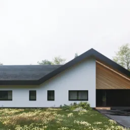 Nowoczesny dom jednorodzinny z białymi ścianami, czarnym dachem i drewnianymi elementami elewacji, otoczony bujną zielenią i kwitnącymi kwiatami, z dwoma rowerami opartymi o ścianę garażu.