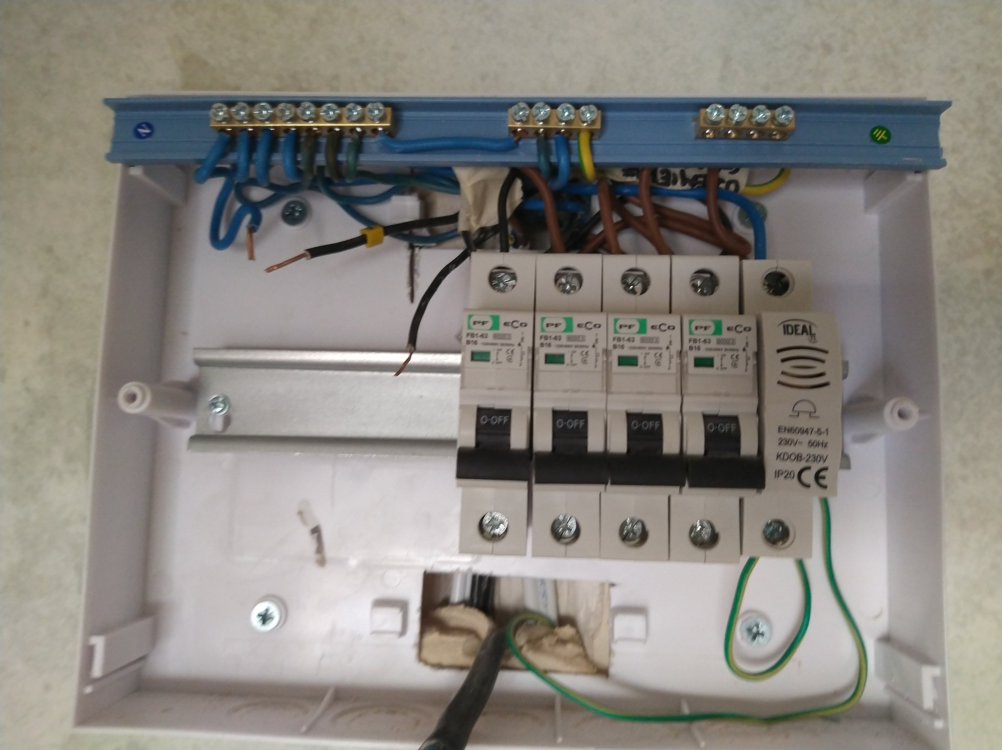 Rozdzielnica elektryczna w trakcie montażu: widoczne bezpieczniki, przewody oraz listwy zaciskowe.  Detale instalacji elektrycznej, skrzynka bez pokrywy.