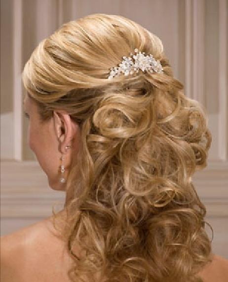 Uczesanie ślubne: blond włosy upięte w loki z ozdobną spinką z pereł i kryształków, widoczne kolczyki z perłami.