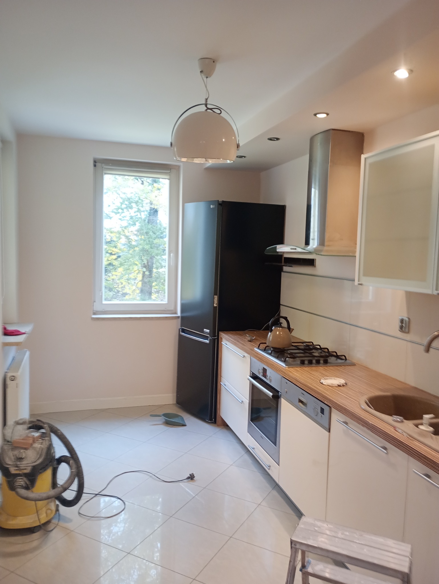 Kuchnia w trakcie remontu: widoczny odkurzacz przemysłowy, świeżo pomalowane ściany, nowe meble kuchenne i sprzęt AGD.