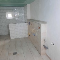 Zakład Usług Leśnych Robert Kowalski,Usługi budowlane - Wnętrze łazienki w trakcie remontu: ułożone płytki podłogowe i ścienne typu metro, widoczne instalacje wodne i elektryczne, sufit w trakcie malowania.
