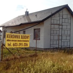EXIGOBUD RAFAŁ STEFAŃSKI - Dom jednorodzinny w trakcie budowy, z zamontowanym rusztowaniem przy ścianie szczytowej, widoczny baner informacyjny z numerem telefonu.
