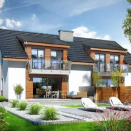 Dwukondygnacyjny dom modułowy z białymi ścianami i drewnianą elewacją, czarnym dachem dwuspadowym, balkonami z balustradami ze szkła, widok z poziomu ogrodu z dwoma leżakami i roślinnością ozdobną.