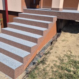 EPOXYPLANET Posadzki żywiczne Kamil Burda - Schody wejściowe wykończone brązowo-szarą posadzką z żywicy, prowadzące do domu z brązową elewacją. Widoczna drenażowa warstwa przy schodach.