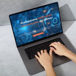 KARO-DIGITAL Projektowanie stron internetowych - Osoba pisze na laptopie, na ekranie widoczna strona internetowa z hasłem 'Profesjonalne technologie informatyczne dla biznesu' na tle grafiki w odcieniach niebieskiego.