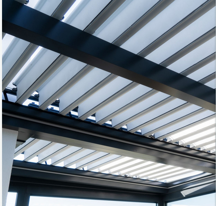 Nowoczesna pergola z metalową konstrukcją i regulowanymi lamelami, widok od dołu, z widocznymi oknami w tle.
