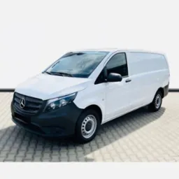 Biały Mercedes Vito, widok z boku, zaparkowany na szarej kostce brukowej, z widocznym logo Mercedesa na grillu i ciemnym, matowym zderzakiem.