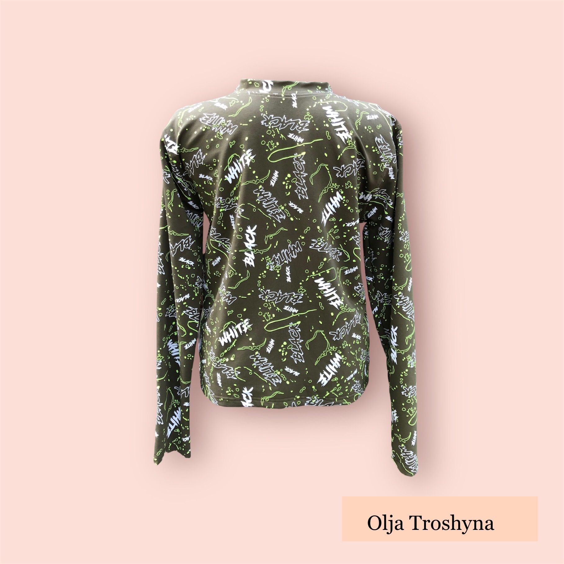 Zdjęcie z tyłu oliwkowej bluzy z długim rękawem, pokrytej białymi i czarnymi napisami oraz neonowymi zielonymi wzorami, na różowym tle.