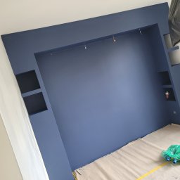 Mar-mont - Niebieska ściana z wnękami i zamontowanymi punktami świetlnymi, zabezpieczona podłoga folią malarską, widoczne kable od oświetlenia