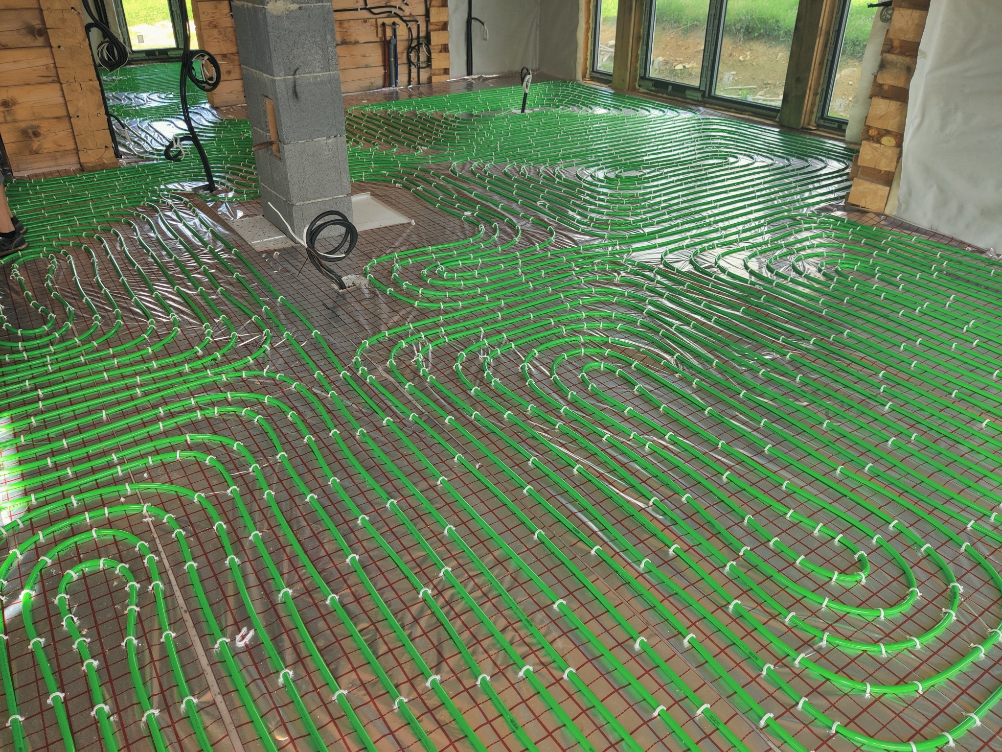 Zielone rury ogrzewania podłogowego rozłożone na siatce w nowym domu w Barcicach Dolnych, widok z góry, przygotowane do zalania wylewką.