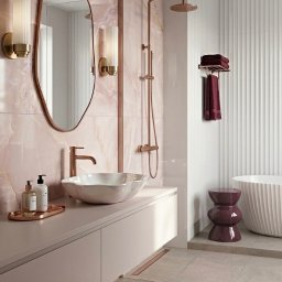 Łucja Orkisz Prim Area Studio - Elegancka łazienka w odcieniach różu i miedzi. Umywalka w kształcie muszli, armatura w kolorze miedzi, marmurowe płytki i designerskie oświetlenie.