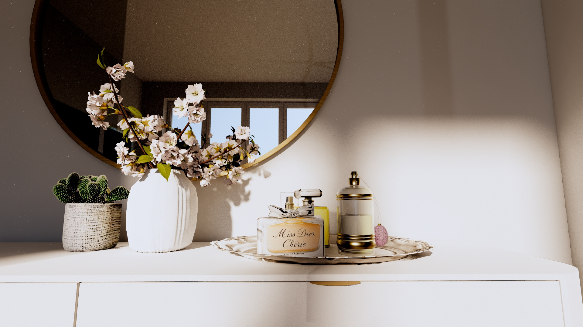 Biała komoda z okrągłym lustrem, wazonem z kwitnącymi gałązkami i kaktusem w doniczce; na tacy flakon perfum Miss Dior Chérie i złoty pojemnik.