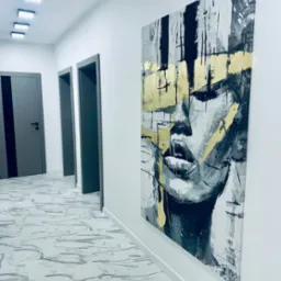 Abstrakcyjny portret kobiety z elementami złota na płótnie, wiszący w korytarzu w Wysocku Małym. Widoczne drzwi i marmurowa podłoga.