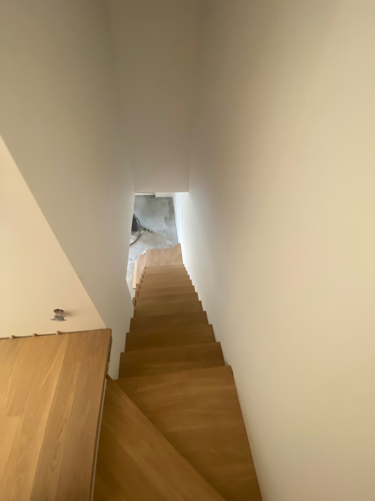 Wysoki kąt widzenia na drewniane schody w trakcie montażu, widoczne niedokończone wykończenia i narzędzia w tle.