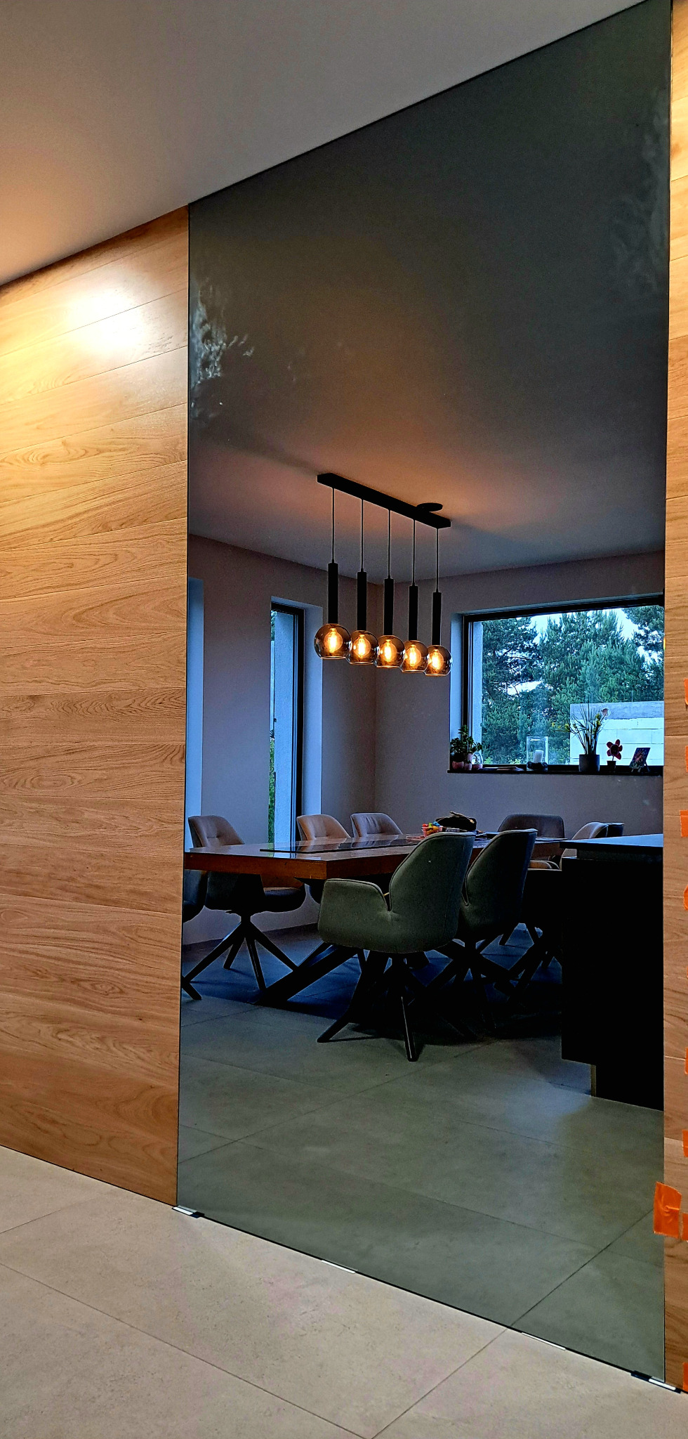 Duże przesuwne drzwi lustrzane oddzielające salon od drewnianego korytarza, widoczne pomarańczowe przyssawki montażowe na krawędzi.