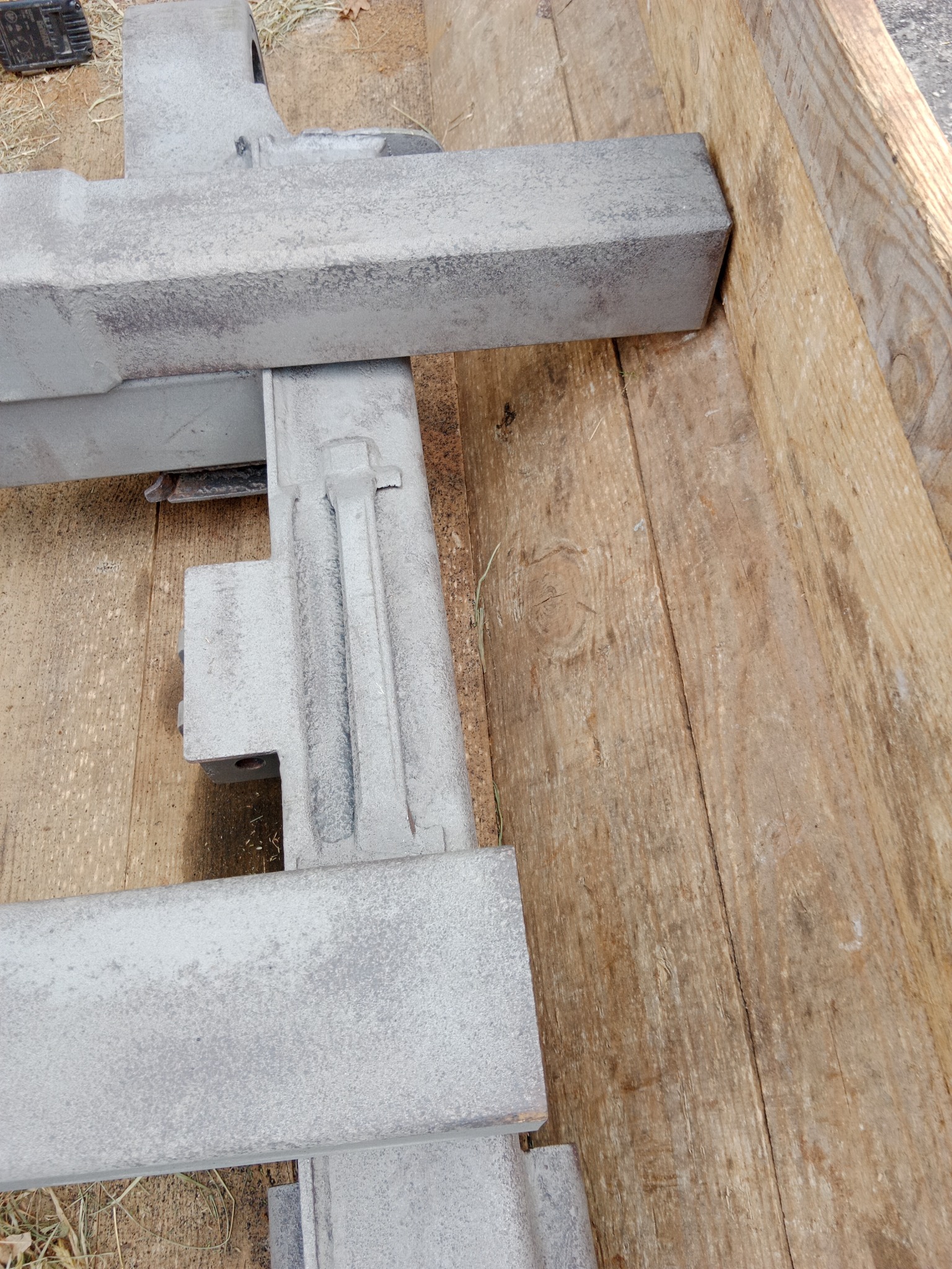 Metalowa konstrukcja po obróbce ściernej, leżąca na drewnianej palecie, widoczne ślady po procesie czyszczenia.