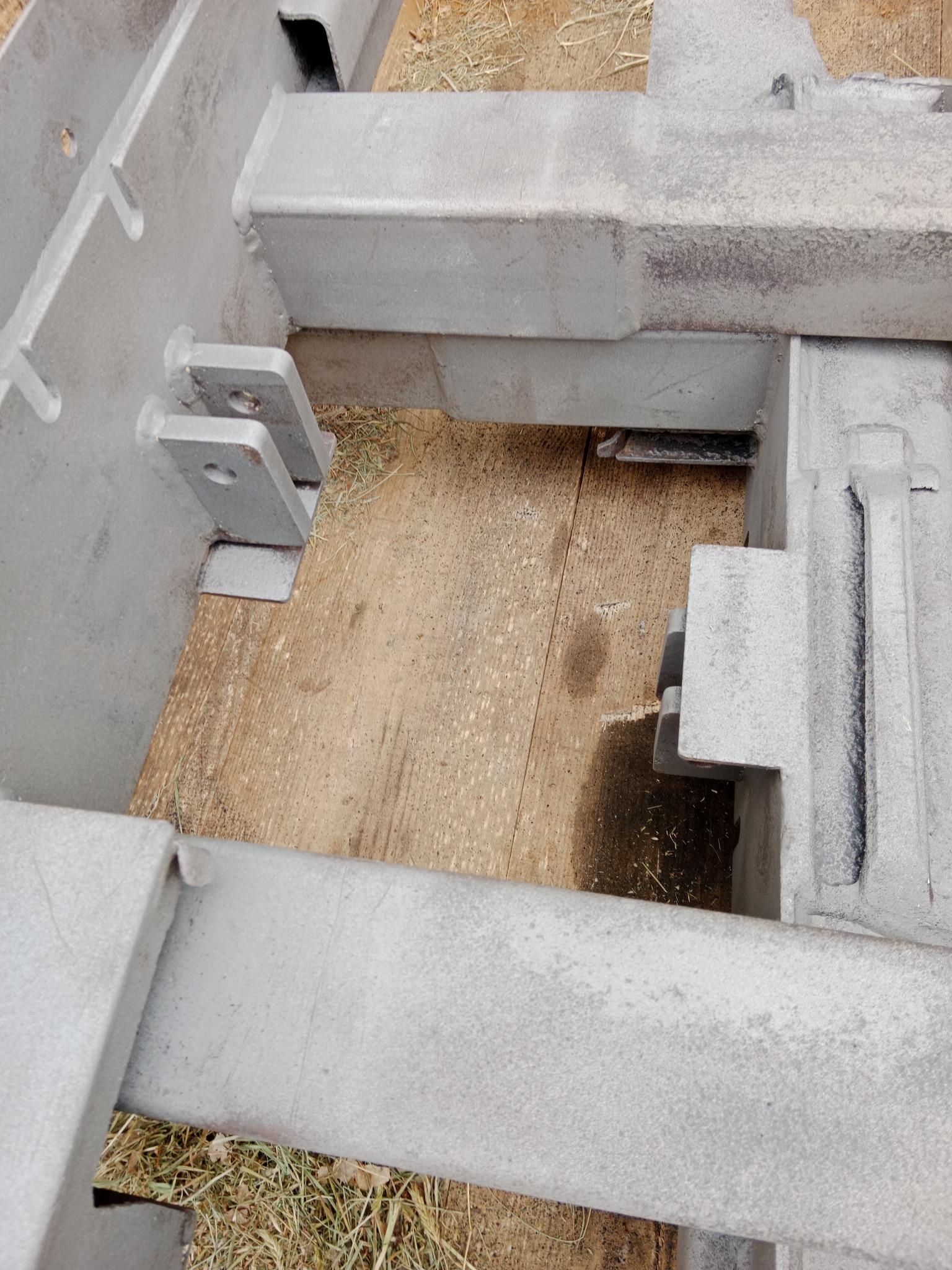 Szare, metalowe elementy konstrukcyjne po obróbce, leżące na drewnianej powierzchni. Widoczne ślady po procesie czyszczenia.