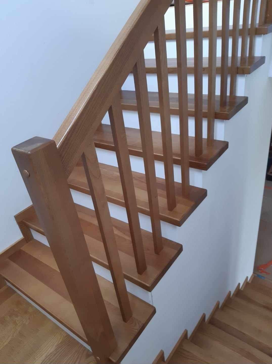 Jasne, drewniane schody z prostą balustradą z pionowych szczebli, widok z góry, minimalistyczny design.