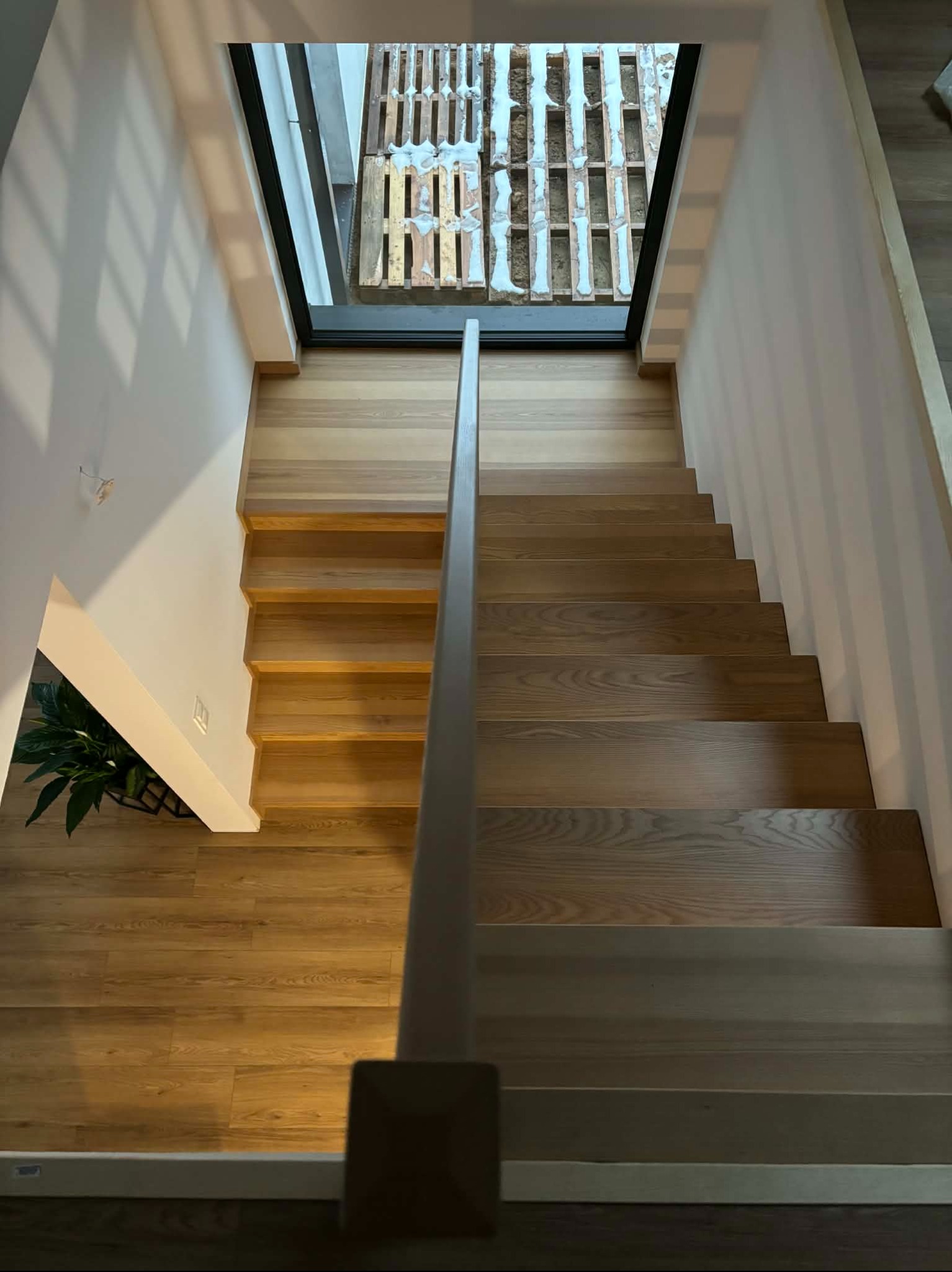 Nowoczesne schody z jasnego drewna, widok z góry. Minimalistyczny design, naturalne światło z okna dachowego. Elementy wykończenia wnętrz w neutralnej kolorystyce.