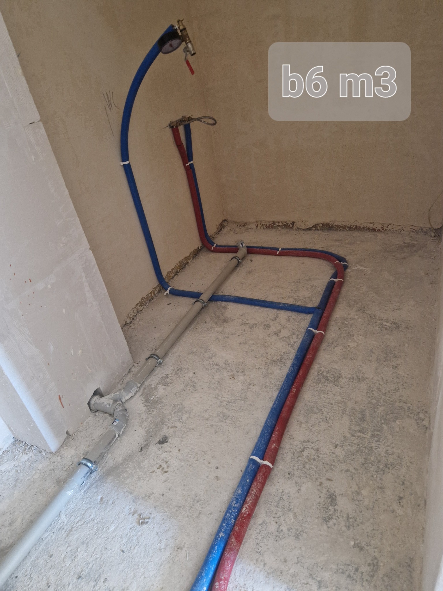 Fragment instalacji wodnej z rurami PEX w kolorze niebieskim i czerwonym, oraz szarej rury kanalizacyjnej, zamontowanej w surowym stanie w Sierakowicach.