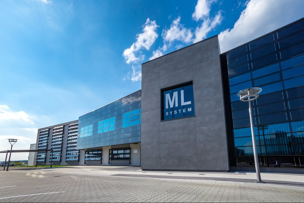 Nowoczesny budynek biurowy ML System z fasadą z paneli fotowoltaicznych, błękitne niebo z chmurami w tle.