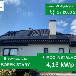 Instalacja fotowoltaiczna na dachu domu jednorodzinnego w Zaczerniu, widoczny komin i panele słoneczne. Zwraca uwagę zielony baner z informacjami o lokalizacji i mocy instalacji.