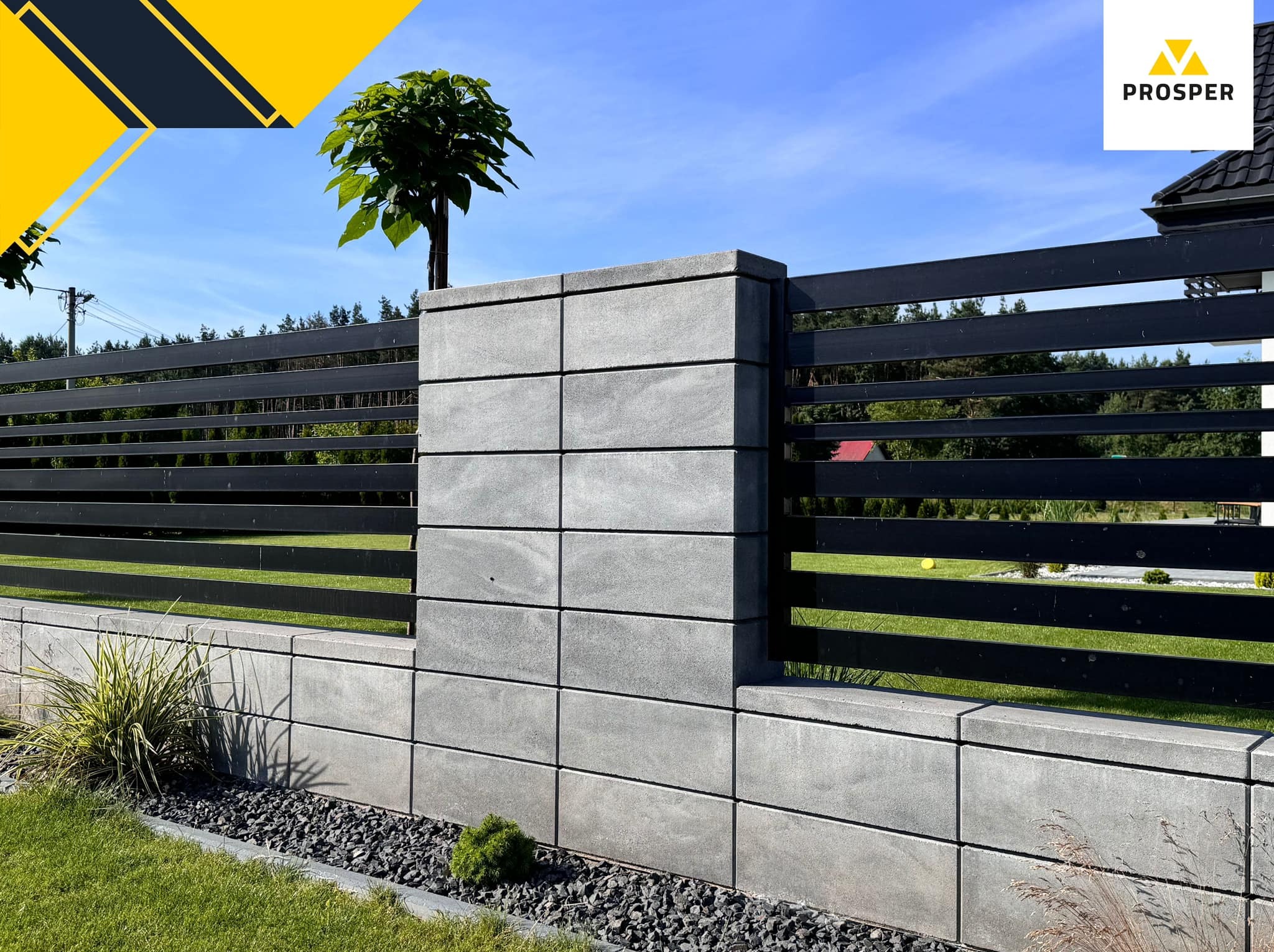 Nowoczesne ogrodzenie z betonowych bloczków i poziomych, czarnych przęseł, z nasadzeniem drzewka na jednym ze słupków, obok rabata z roślinami i czarnym grysem.