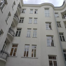 MIPAS-BUD VOLODYMYR PASHCHUK - Elewacja kamienicy po remoncie, widok z dołu ukazuje odnowioną fasadę z balkonami i oknami, podkreślając czystość bieli i architektoniczne detale.