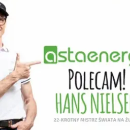 Hans Nielsen, 22-krotny mistrz świata na żużlu, poleca Astaenergy, logo firmy widoczne na czapce i obok, białe tło.