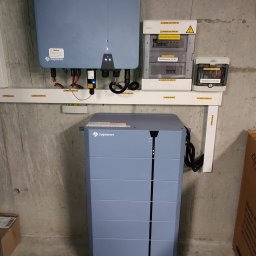 ASTA ENERGY SYSTEMS SPÓŁKA Z OGRANICZONĄ ODPOWIEDZIALNOŚCIĄ - Kompletna instalacja: falownik, rozdzielnice AC/DC i magazyn energii Solplanet na surowej ścianie. Widoczne okablowanie i oznaczenia napięć.