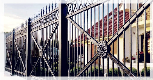 Eleganckie, kute ogrodzenie z ozdobnymi rozetami na tle domu z czerwoną dachówką.