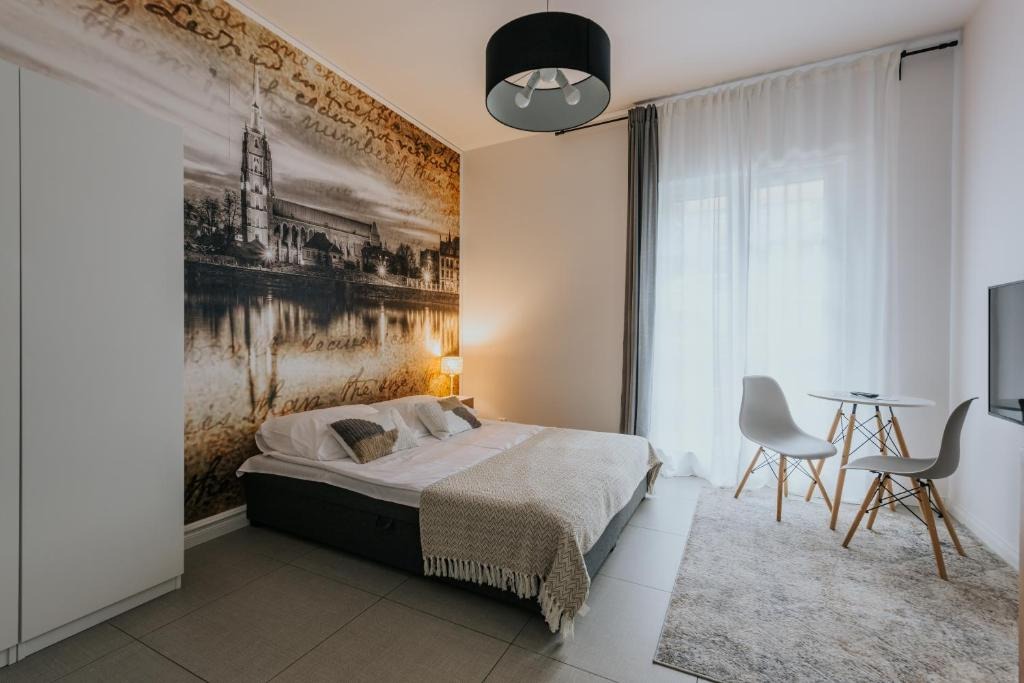 Sypialnia z fototapetą przedstawiającą zabytkową architekturę nad rzeką, minimalistyczne meble i okrągłą lampę sufitową.